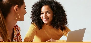 Two young professional women discussing in front of a laptop