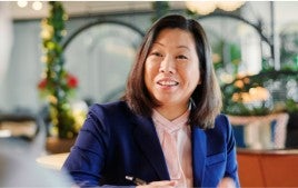 A recruiter taking notes and smiling while interviewing a potential candidate.