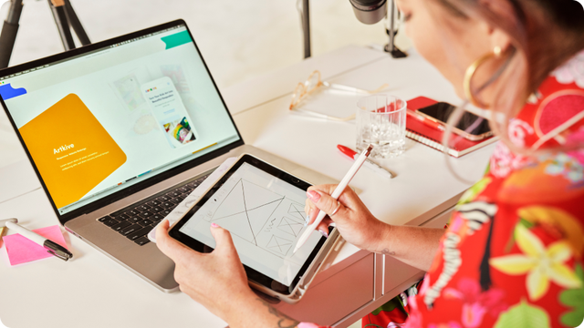 photo of a person working on a laptop and tablet at a desk