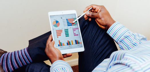 An individual sitting down and looking at analytics on their tablet device.